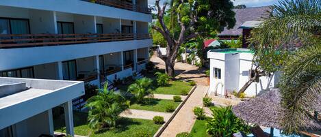 Un hotel con varias plantas, terraza al aire libre y un jardín bien cuidado.