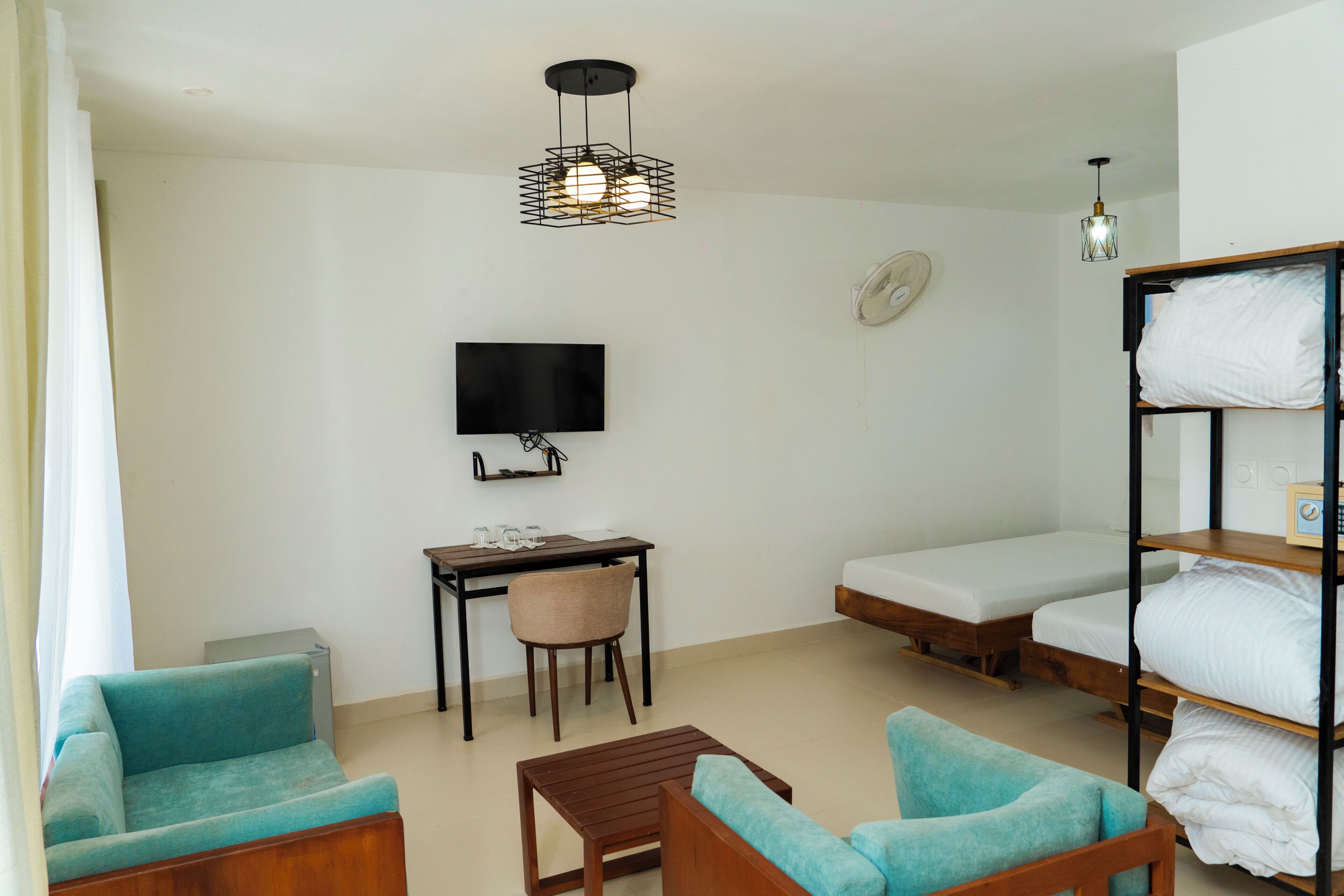 Una habitación con cama, escritorio, silla, televisor y estantería.