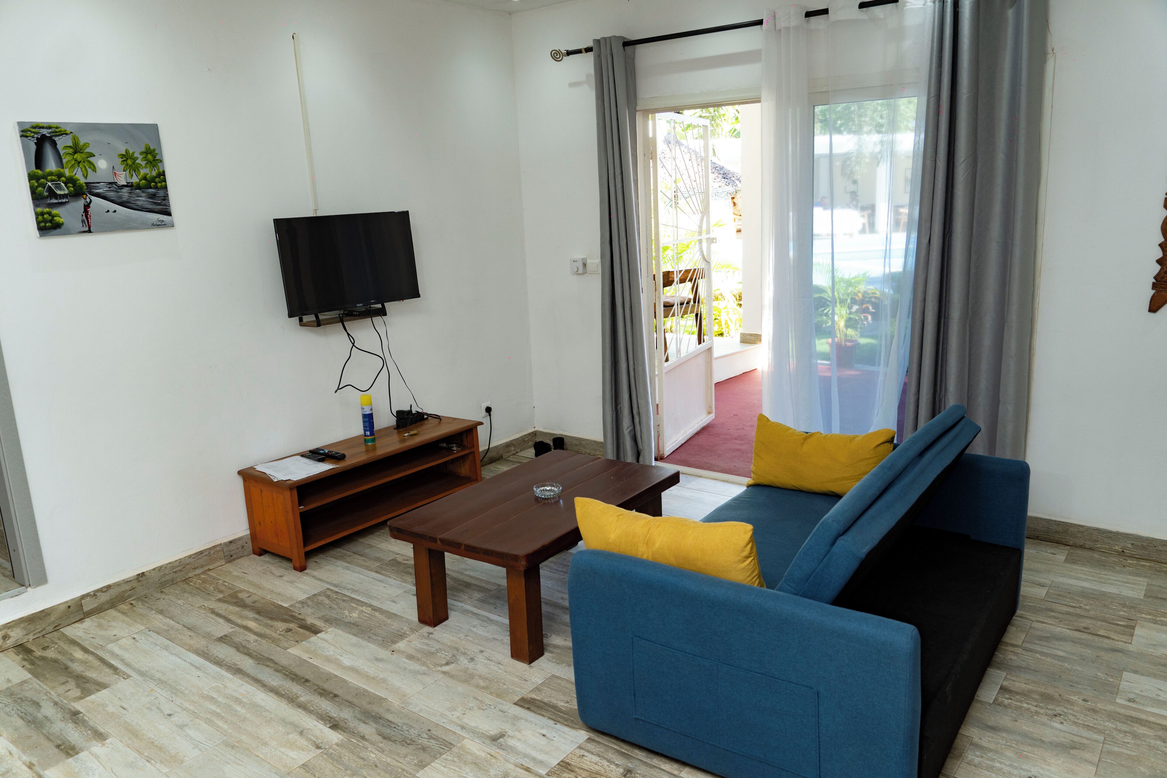 A living room with a sofa, a TV, a wooden coffee table, and a painting on the wall.
