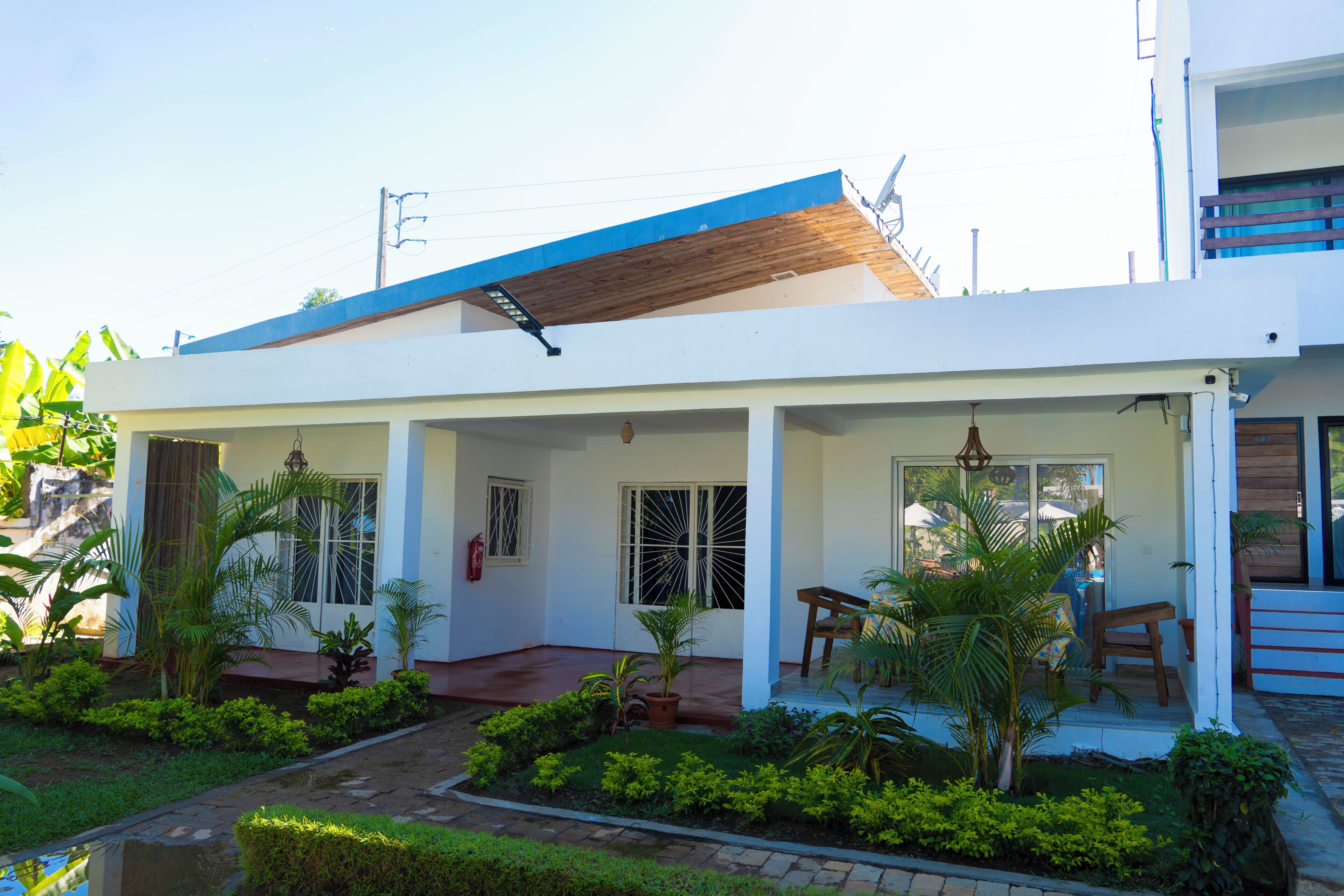 A modern house with a covered porch, a fire extinguisher, and a small garden.