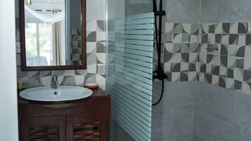 Une salle de bain avec une douche à parois de verre, un lavabo avec un miroir et des carreaux décoratifs sur les murs.