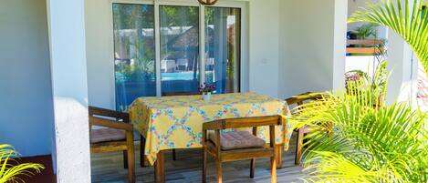 A dining area with a table, chairs, and a view through a glass door.