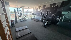 Ein Fitnessstudio mit Trainingsgeräten, Laufband und großem Fenster.