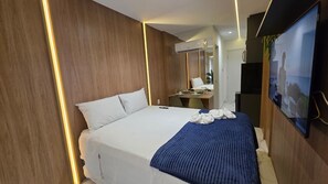 Ein Hotelzimmer mit Bett, Schreibtisch, Fernseher und Klimaanlage.