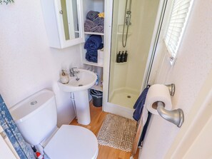 A compact bathroom with a toilet, sink, and shower. - 517 - Promenade Caravan Site (Skegness)