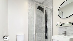 Un baño moderno con ducha envuelta en vidrio, inodoro y tocador con espejo.
