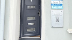 Una puerta negra con el número 12, un letrero que dice 'MARINE VILLA 1887' y un código QR para reservas.