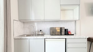 Una cocina moderna con armarios blancos, microondas integrado y lavavajillas.