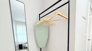 Ein Zimmer mit einer hölzernen Bank, einem Spiegel und einem Wäscheständer.