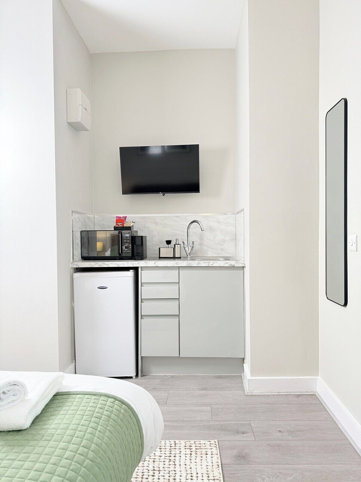 A compact kitchenette with a microwave, coffee machine, and sink.