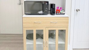 Una cocina con microondas, un mueble con puertas de vidrio y una puerta blanca al fondo.