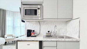 Une petite cuisine équipée d’un micro-ondes encastré, d’un évier et d’un petit réfrigérateur.