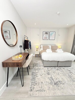 Een moderne hotelkamer met een bed, bureau, stoel en een grote spiegel.