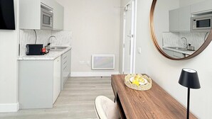Une cuisine moderne dotée d’appareils électroménagers intégrés, un coin repas avec une table en bois et un grand miroir au mur.