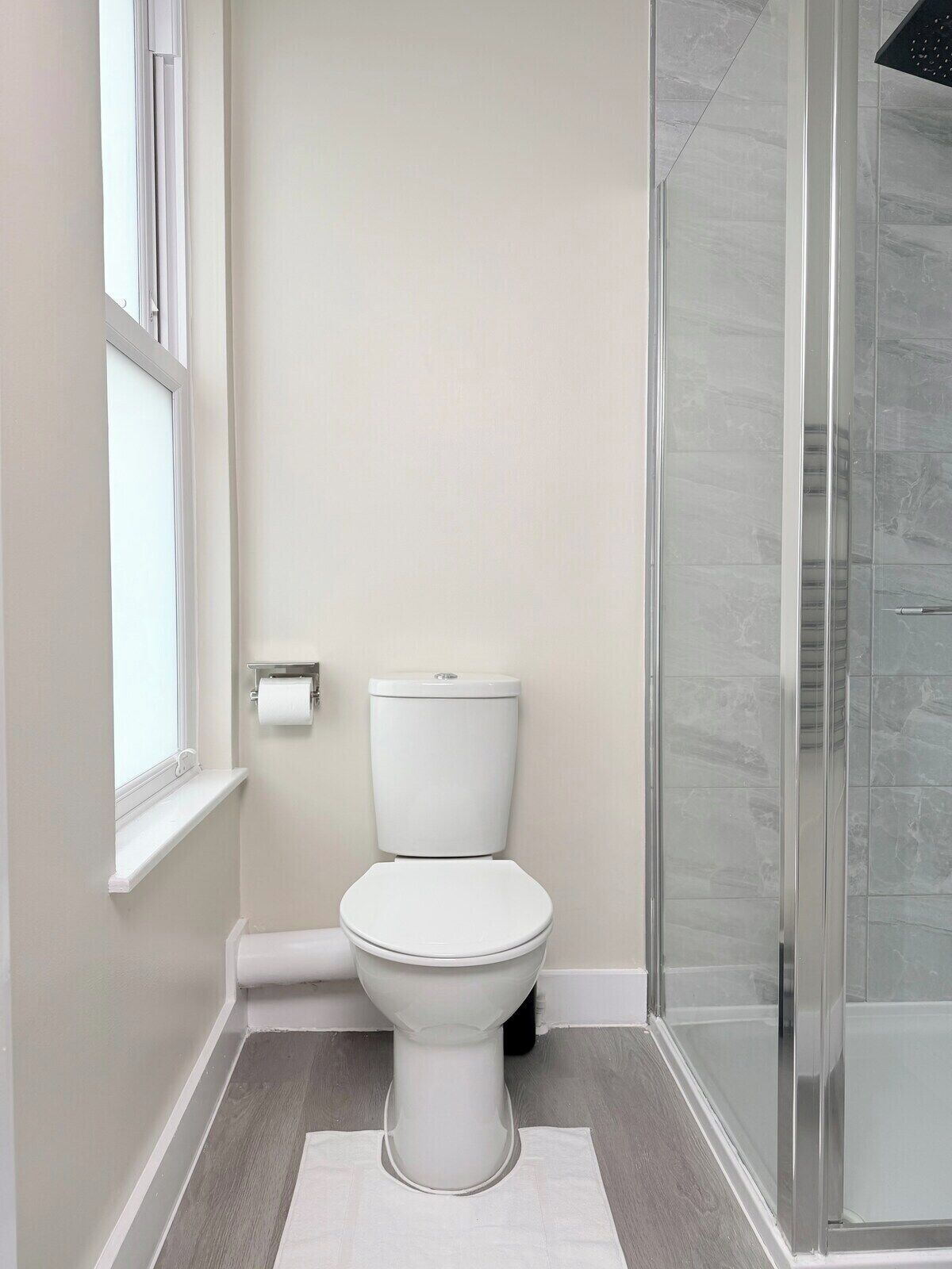 Une salle de bain moderne équipée de toilettes, d’une douche et d’une fenêtre.