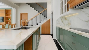 A modern kitchen with a marble countertop, wooden cabinets, and a staircase leading to another level. - P817 Elite Tropical Residence (An Thoi)