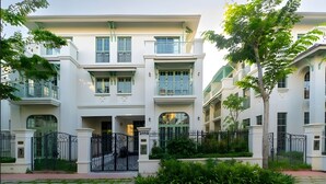 A multi-story building with balconies, a gated entrance, and surrounding greenery. - P817 Elite Tropical Residence (An Thoi)