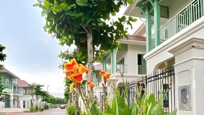 A street lined with lush greenery and a building with a balcony. - P817 Elite Tropical Residence (An Thoi)