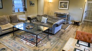 A living room with a sofa, armchair, coffee table, rug, and artwork on the walls. - Stylish Retreat in the Heart of Somerton with Wood Fire (Somerton)