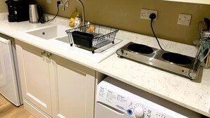 A kitchen with a double sink, a coffee maker, a kettle, a dish rack, and a stove. - Stylish Retreat in the Heart of Somerton with Wood Fire (Somerton)