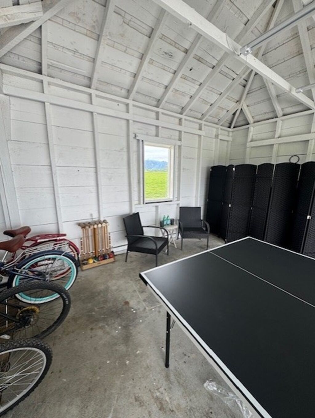 Une pièce équipée d’une table de ping-pong, de vélos et de chaises.
