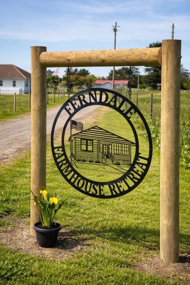 A wooden sign with a circular emblem featuring a house and the text 'FERNDALF FARMHOUSE REALTY'.