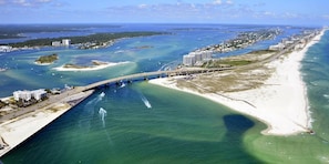 Eine Küstenbrücke, die zwei Landmassen verbindet, mit Strand und Yachthafen auf einer Seite.