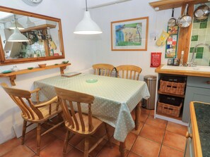 A dining area with a table covered by a polka-dotted tablecloth, surrounded by wooden chairs. - St. Dominic Cottage (St Ives)