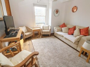 A living room with a sofa, chairs, a coffee table, a TV on a stand, and a window. - St. Dominic Cottage (St Ives)