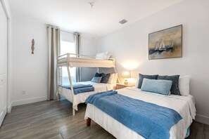 A bedroom with bunk beds, a bedside table with a lamp, and a painting on the wall. - Stylish Newly Built Retreat (West Palm Beach)