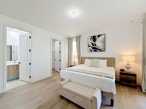 A bedroom with a bed, bedside tables, a bench, a mirror, and a door leading to another room. - 15261 Brainbridge Circle, Port Charlotte, FL 33981 (Charlotte County)