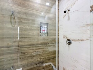 A shower with a glass door, a marble wall, and a showerhead. - 15261 Brainbridge Circle, Port Charlotte, FL 33981 (Charlotte County)