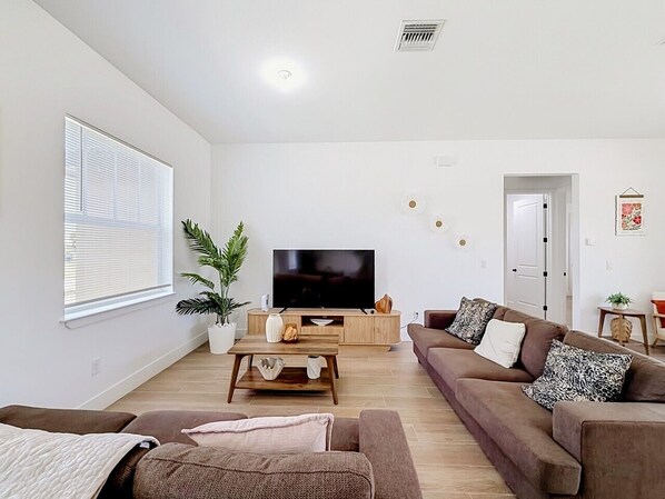 A modern living room with a flat-screen TV, two sofas, a coffee table, and a potted plant. - 15261 Brainbridge Circle, Port Charlotte, FL 33981 (Charlotte County)