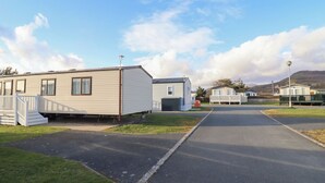 A caravan park with multiple caravans, a paved road, and grassy areas. - 23 Gull Court (Porthmadog)