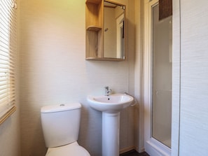 Ein Badezimmer mit Toilette, Waschbecken und einer Duschkabinentür aus Glas.