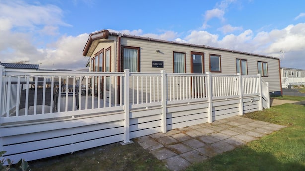A mobile home with a white deck and a fenced patio area. - 23 Gull Court (Porthmadog)
