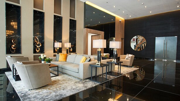 Un hall d’hôtel moderne, aménagé avec un ensemble de canapés, deux tables d’appoint, une table basse et un grand miroir.