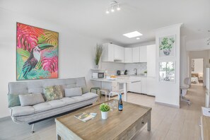 Een moderne woonkamer met een bank, salontafel en een levendig tropisch kunstwerk.