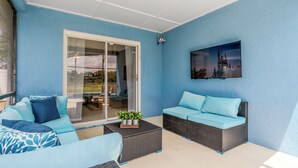 Un porche cubierto con una pared azul, una puerta de cristal que da a un espacio exterior y un cuadro colgado de un castillo.