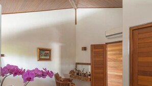 A modern interior with a wooden ceiling, a dining area with a chair, a small table, a mirror, a shelf with toiletries, and a large rug. - House with sea and cliff views, 100m from the beach in Trancoso. (Trancoso)