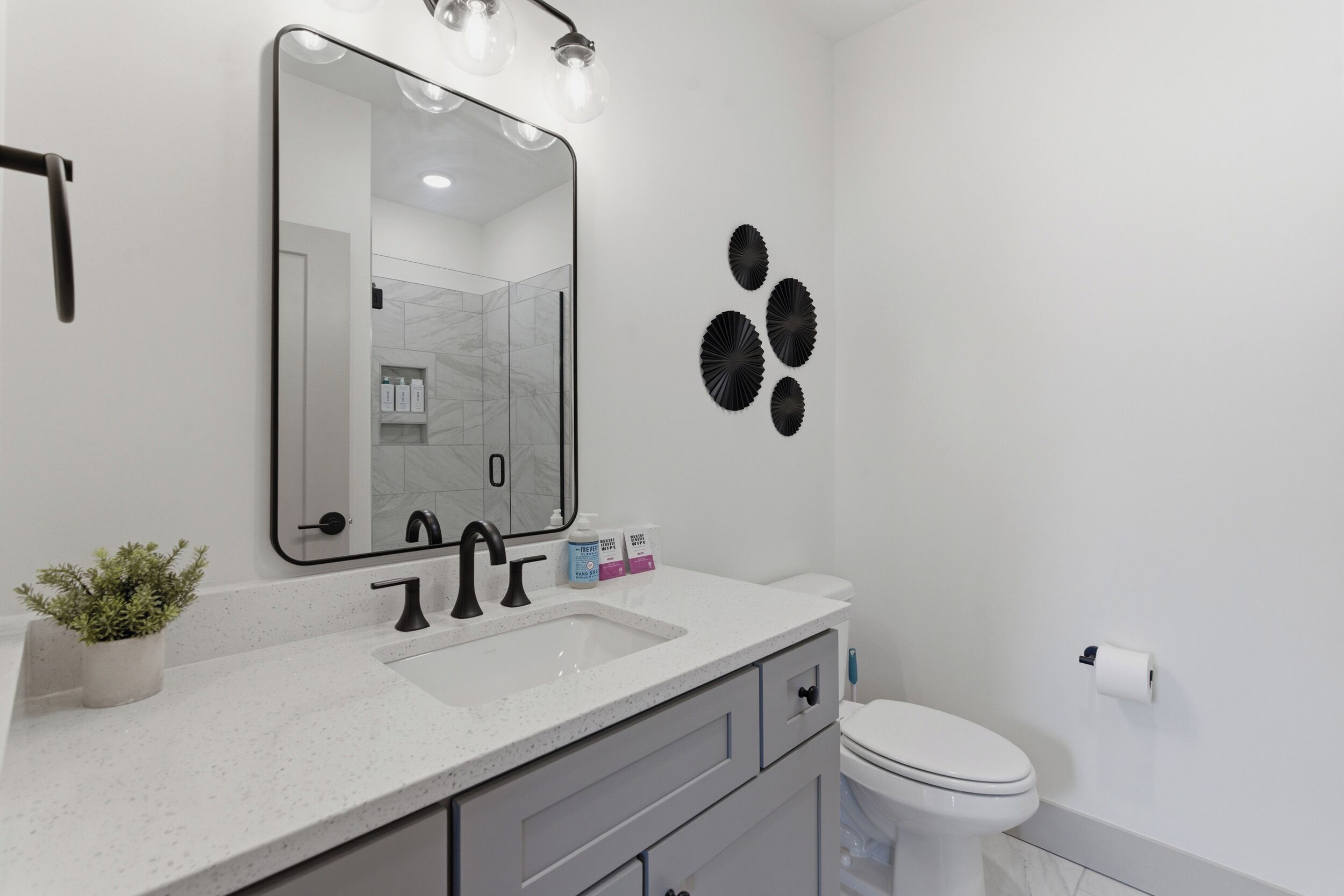 Une salle de bain avec un lavabo blanc, un miroir, des toilettes et des éléments décoratifs sur les murs.