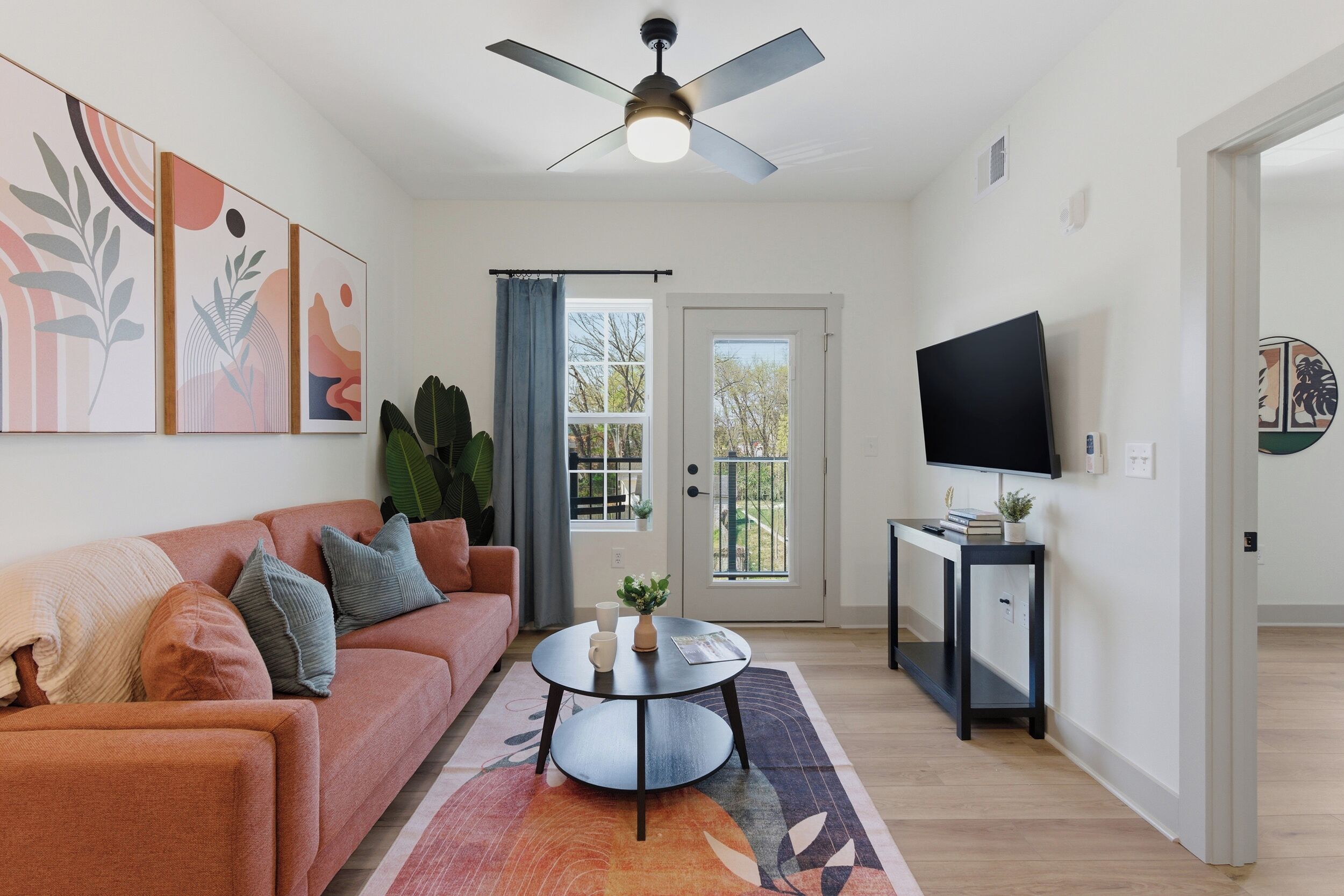 A living room with a sofa, coffee table, ceiling fan, TV, and artwork on the wall.