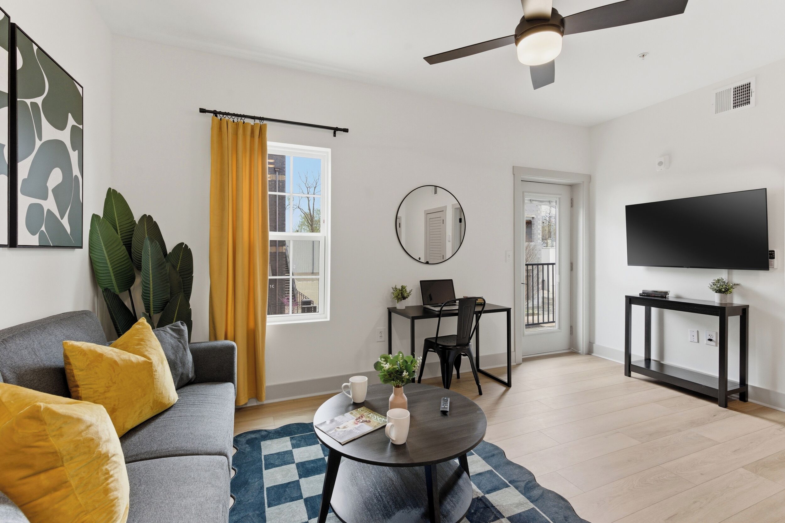A modern living room with a sofa, coffee table, and a dining area with chairs and a table.