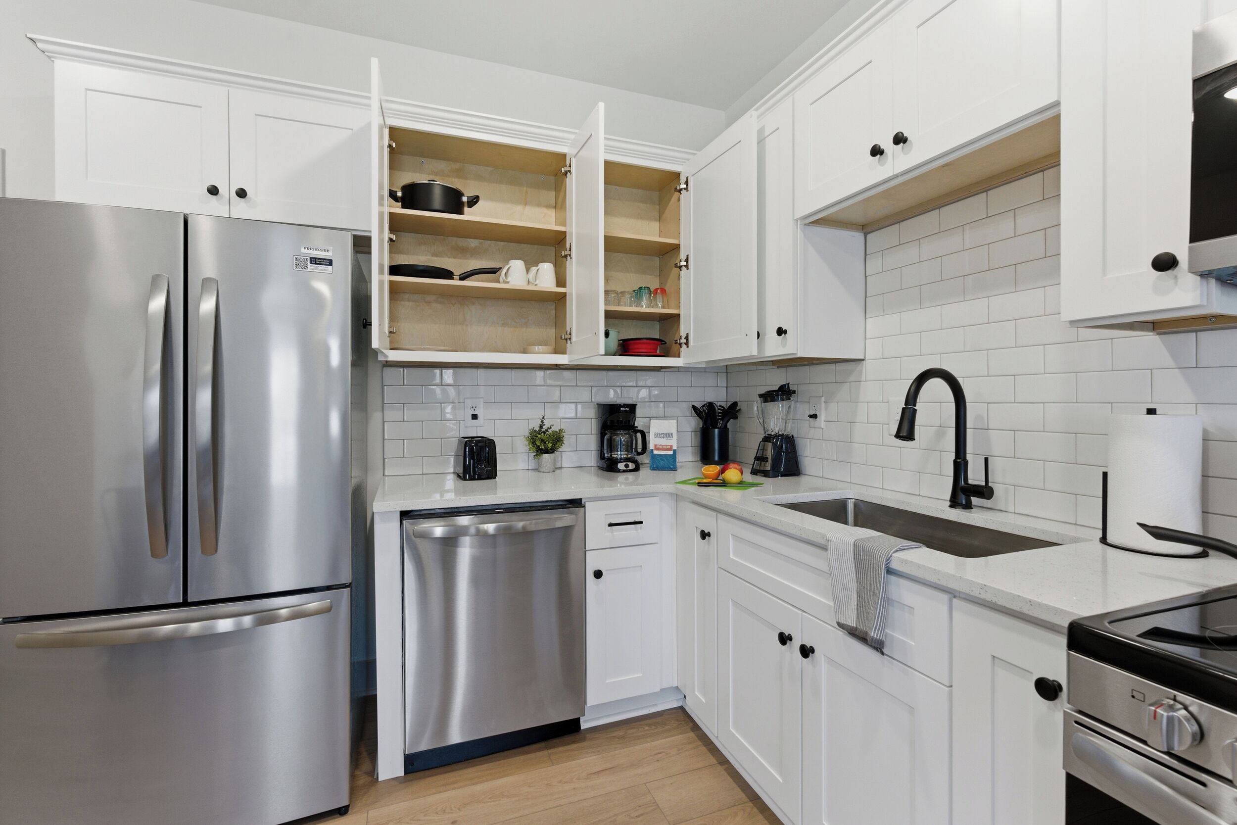 A modern kitchen with white cabinets, stainless steel appliances, and a built-in oven.