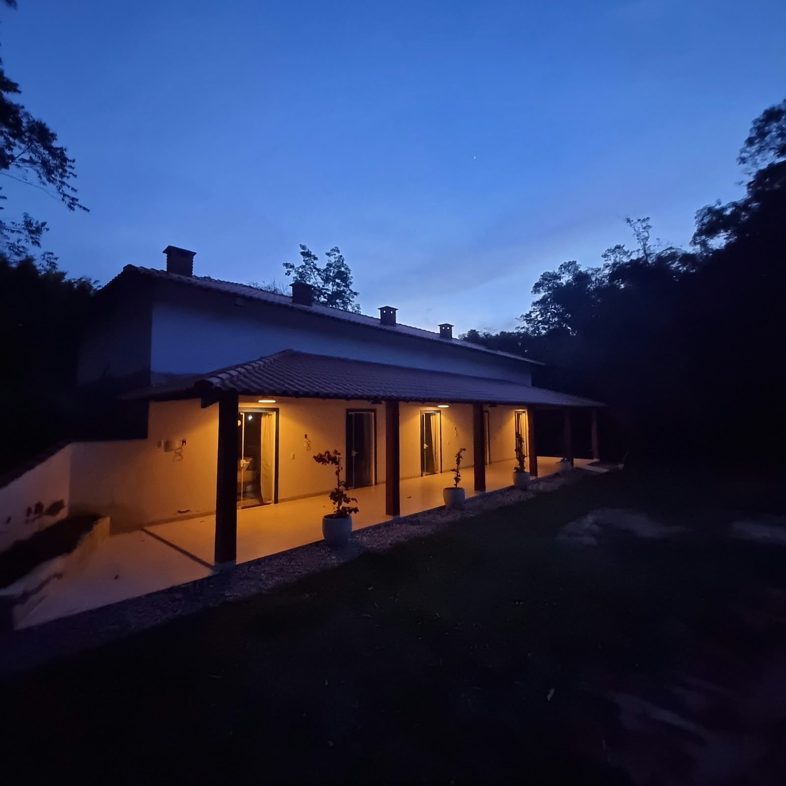 A two-story house with a covered porch and a small garden area.