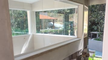 Habitación con un amplio ventanal con vistas a un jardín, chimenea y un cubo verde.