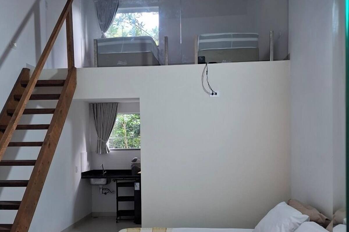 A bedroom with a bunk bed, a desk with a chair, and a window with curtains.