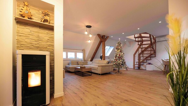 A living room with a fireplace, a sofa, a Christmas tree, and a wooden staircase.