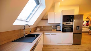 A modern kitchen with a skylight, stainless steel appliances, and wooden flooring.