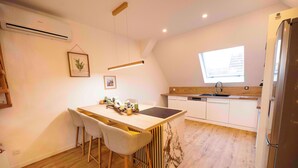 A modern kitchen with a central island, bar stools, a window, and a refrigerator.